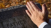 Grieving son at father's gravestone