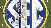 FILE - Auburn quarterback Nick Marshall (14), left, takes the snap from Auburn center Reese Dismukes (50) as the Auburn offense operates against Missouri on the SEC logo during the first half of Auburn's 59-42 win over Missouri in the SEC Championship at the Georgia Dome, Saturday, Dec. 7, 2013, in Atlanta, Ga. Southeastern Conference and Pac-12 officials are expected to provide the final approval of a $2.8 billion plan that will settle antitrust claims and set the stage for college athletes to start sharing the billions of dollars flowing to their schools. (AP Photo/Atlanta Journal-Constitution, Jason Getz, File)